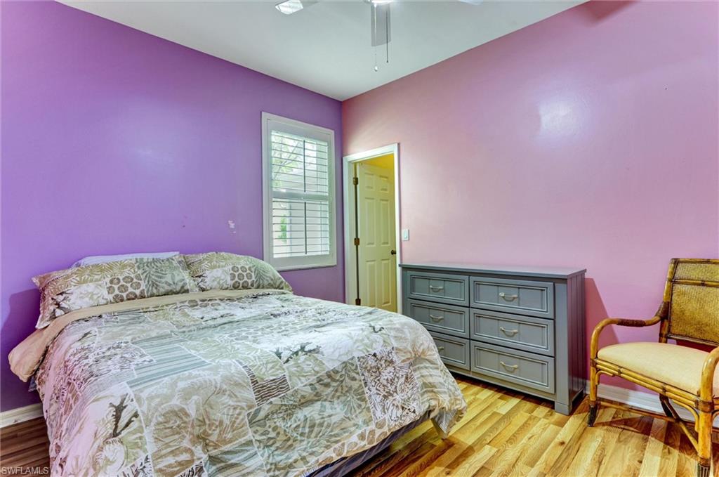 Hardwood flooring, window with plantation shutters, ceiling fan, and painted walls