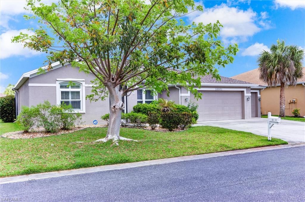 Single-story stucco exterior with a two-car garage, manicured lawn, and mature landscaping