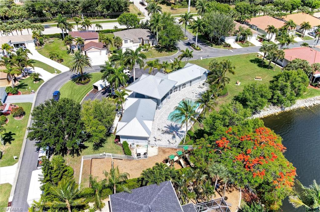 Community Center with Pool and fitness centerfeaturing a sparkling resort-style pool with mature tropical landscaping, expansive manicured lawn, and a modern white pergola structure