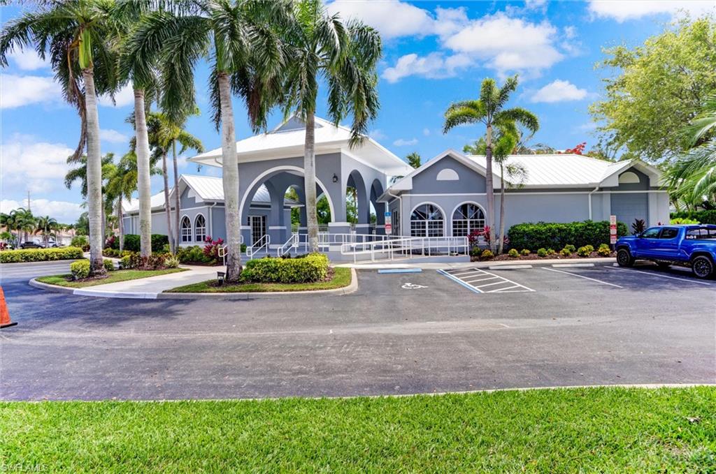 Community Center with Pool and fitness center. Building exterior featuring multiple arched entryways, a light gray facade, a white metal roof, and surrounding palm trees