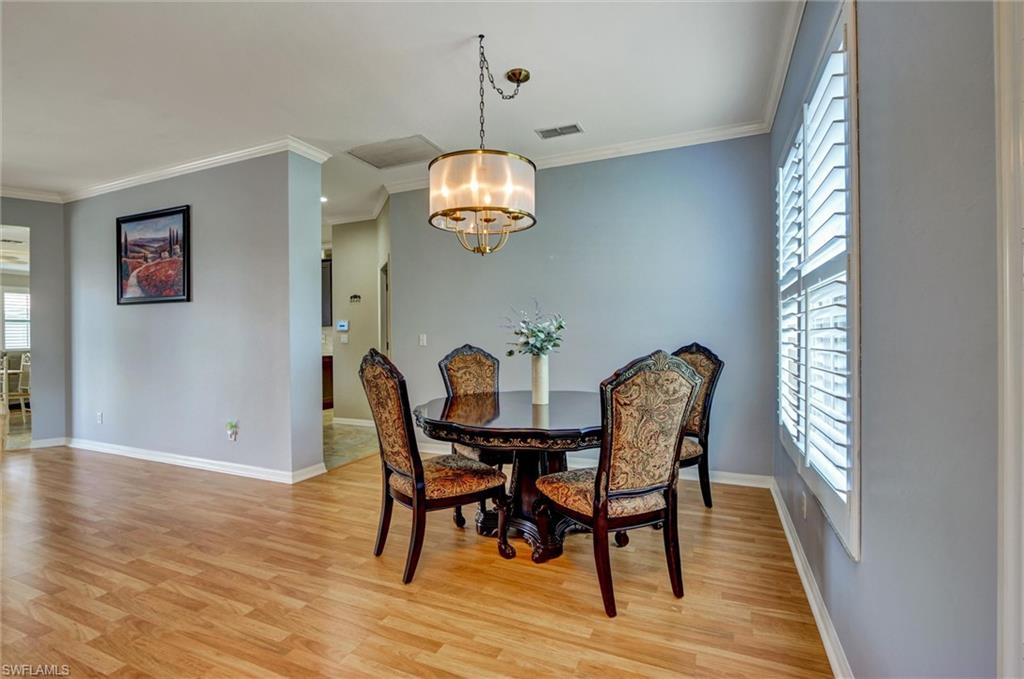 Elegant dining room showcasing warm wood-finish flooring, soft blue accent walls, and a pendant light fixture with a brushed metal finish