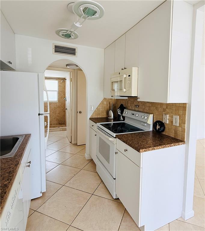 Kitchen featuring white cabinetry, brown speckled countertops, and a tiled backsplash