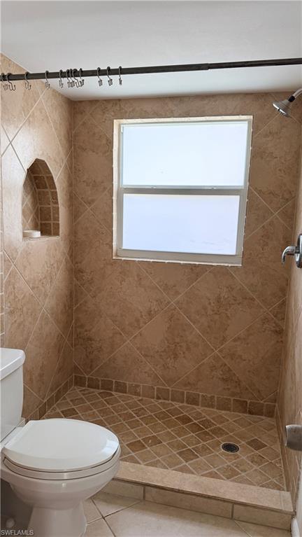 Tiled shower enclosure with an integrated arched niche, a window, and a built-in shower pan