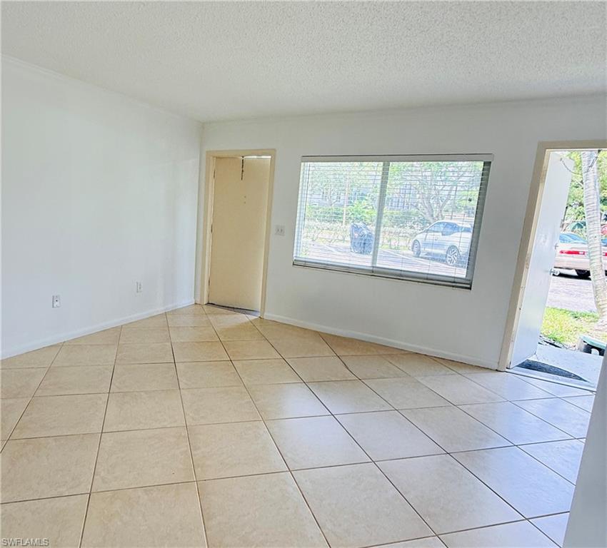 Tile flooring with a neutral finish, white painted walls, and a large window with blinds