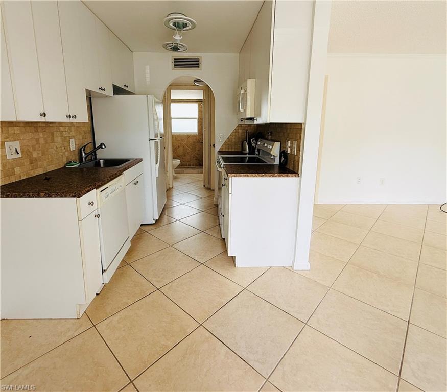 Kitchen featuring white cabinetry, granite-style countertops, mosaic tile backsplash, and tile flooring