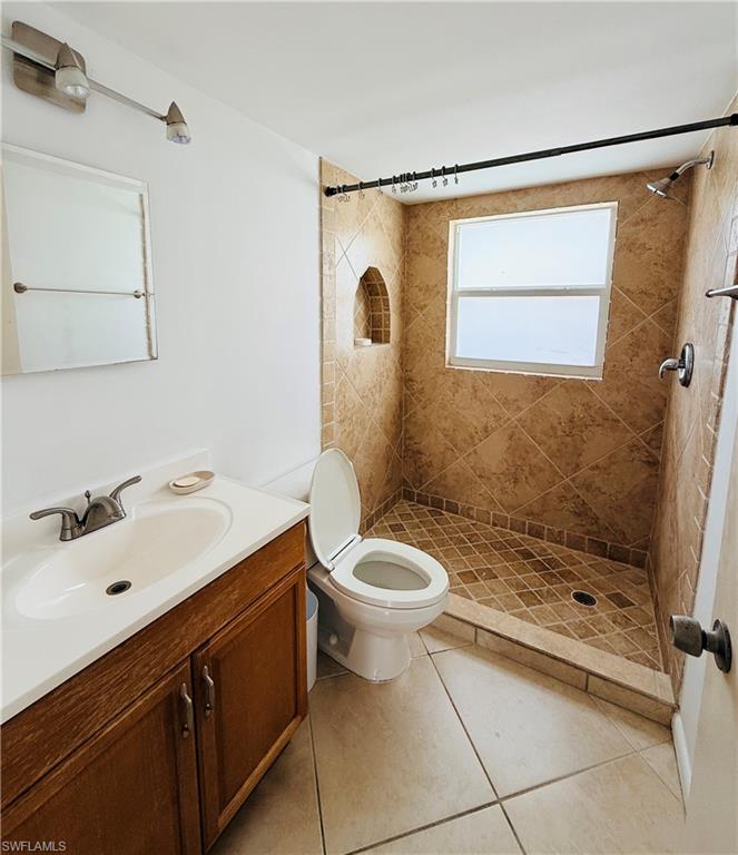 Tiled shower with a window, built-in shower niche, and a vanity with an integrated sink