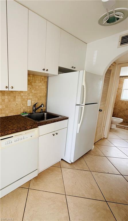 Kitchen featuring white cabinetry, a double basin sink, a built-in dishwasher, and tiled flooring