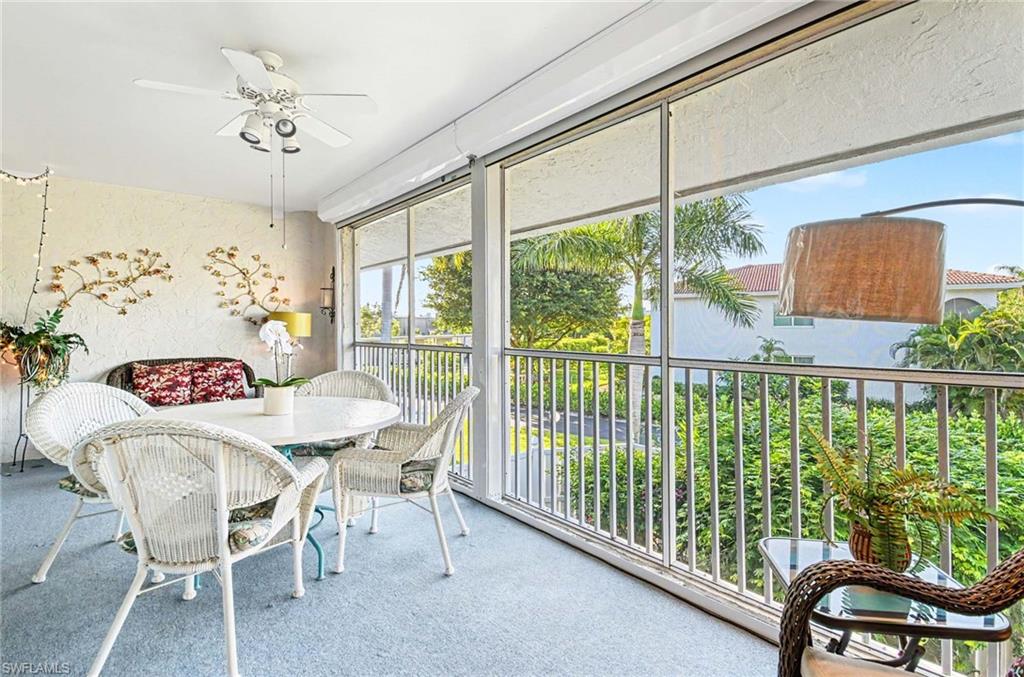 Screened-in balcony with a ceiling fan, textured wall finish, and exterior railing