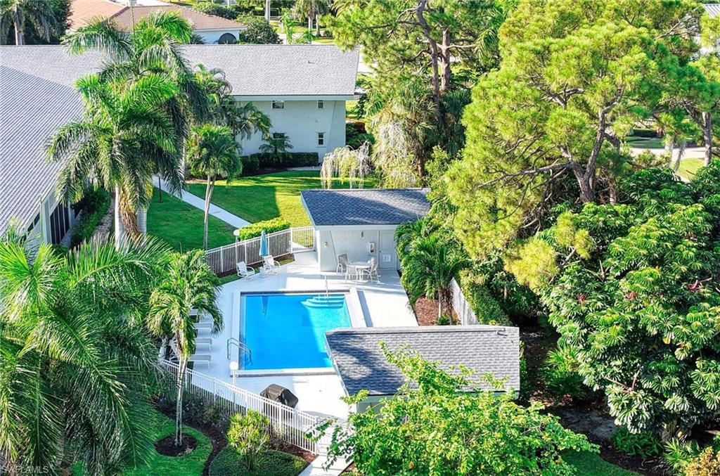 Outdoor swimming pool with integrated spa, surrounded by a white concrete deck and a cabana structure