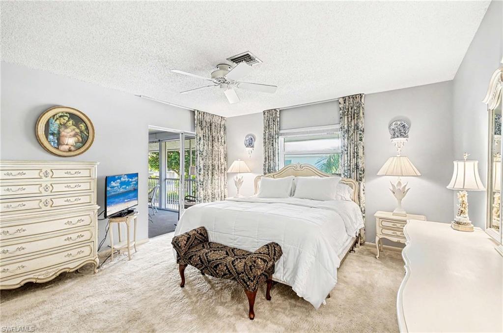 Carpeted flooring, ceiling fan, window with privacy blinds, sliding glass door to an enclosed screened area