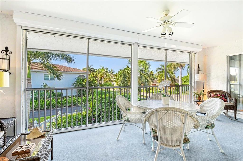 Screened-in outdoor living space with a ceiling fan, sliding glass door, and a decorative wall sconce