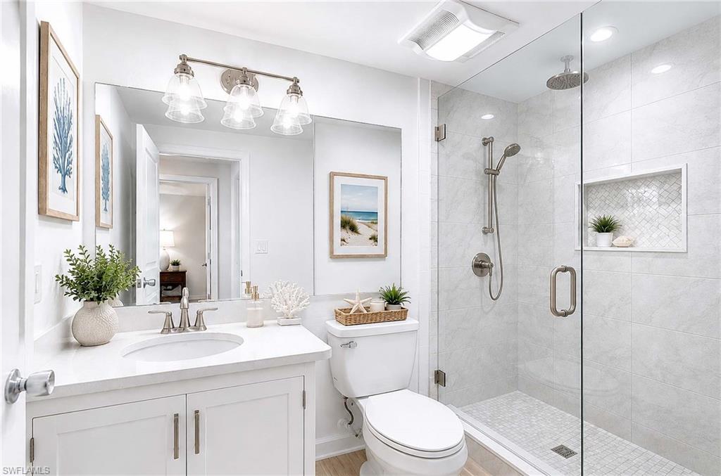 Virtual Renovation: Spacious bathroom featuring a glass-enclosed shower, rain shower head, built-in shower niche, and a white vanity with an undermount sink
