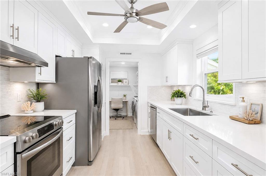 Virtual Renovation: White shaker-style cabinetry with brushed nickel hardware, stainless steel appliances, light wood-finish flooring, and a tray ceiling with recessed lighting