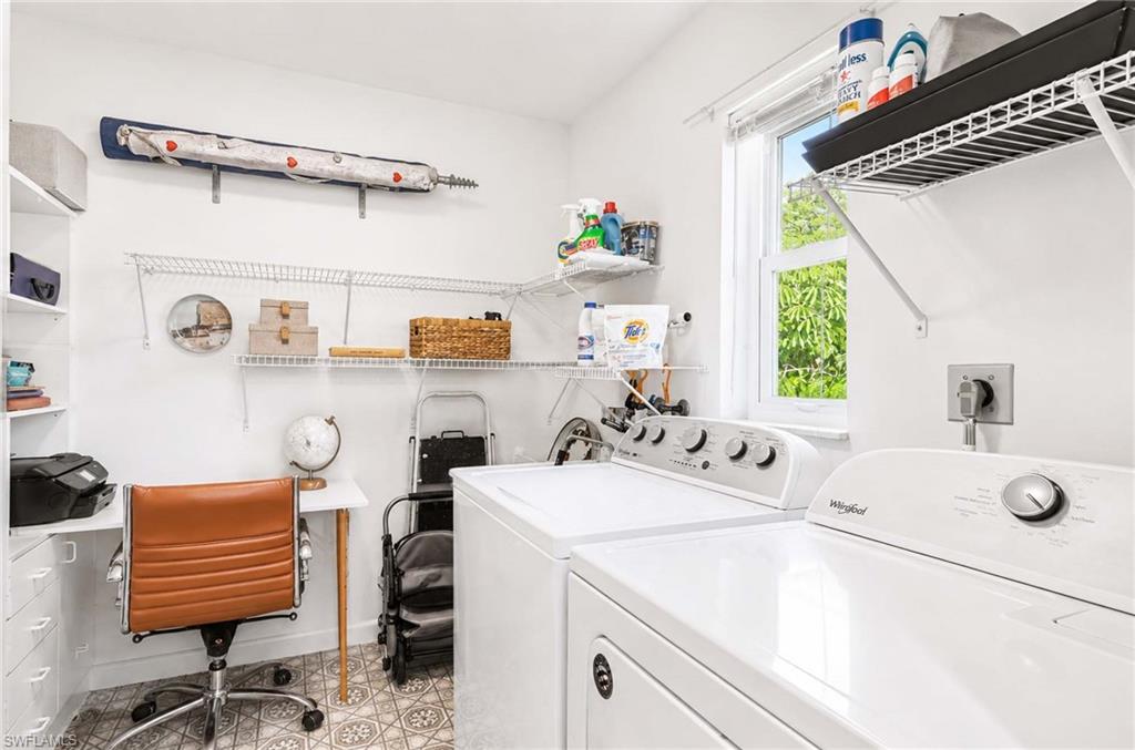 Dedicated laundry area with white appliances, built-in shelving, and a patterned tile floor