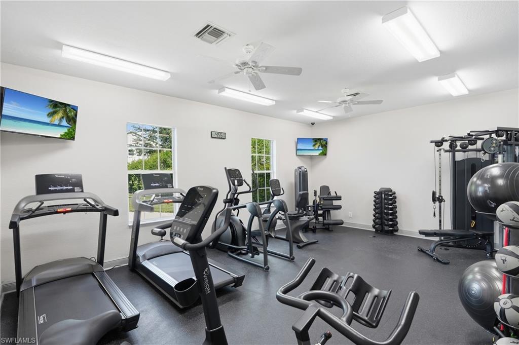 Spacious fitness area featuring multiple windows, recessed lighting, ceiling fans, and durable rubber flooring