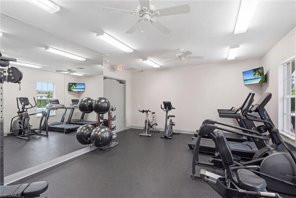 Fitness center with rubber flooring, ceiling fans, and integrated wall-mounted television