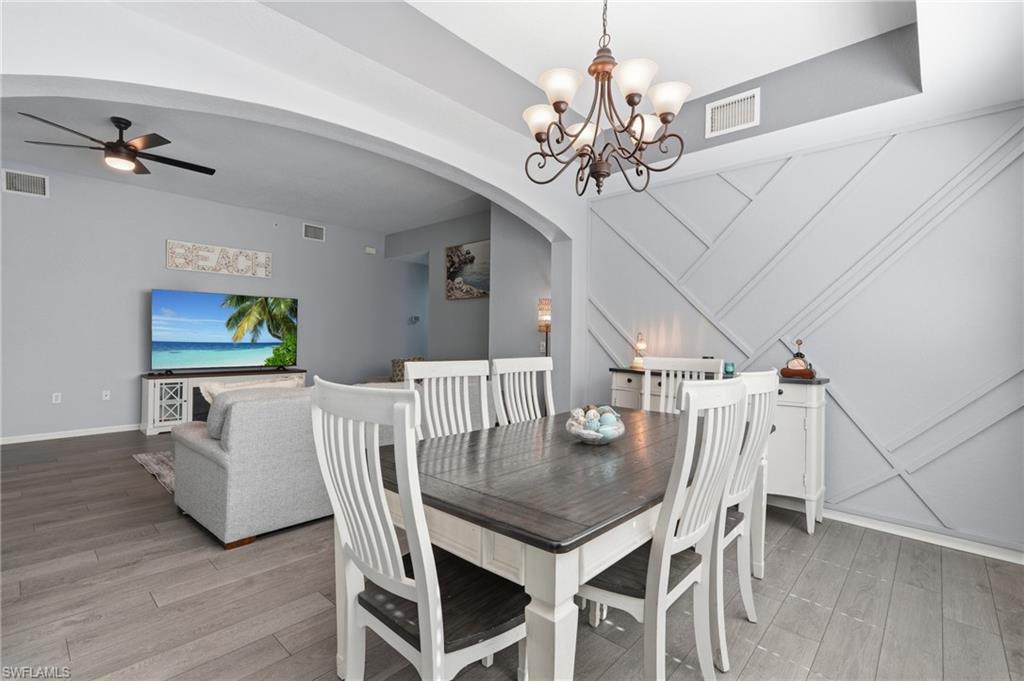 Dining area featuring a decorative accent wall with geometric molding, wood-finish flooring, and a chandelier