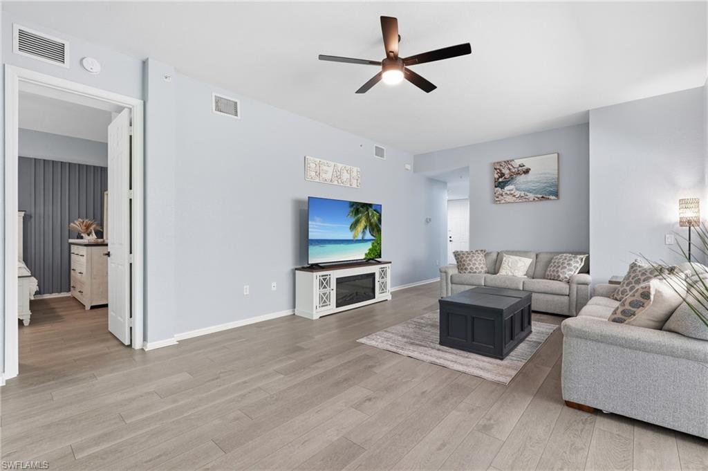 Spacious living area featuring wood-finish flooring, a ceiling fan with light, and light-colored walls