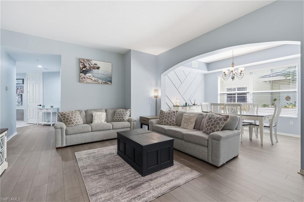 Wood-finish flooring throughout, arched entryway, tray ceiling, and decorative wall paneling