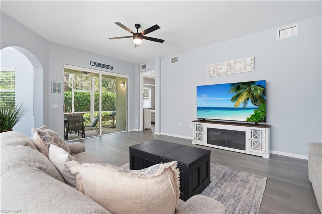 Spacious living area featuring wood-finish flooring and a ceiling fan with integrated lighting