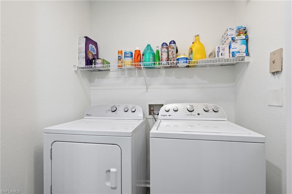 Dedicated laundry room featuring side-by-side washer and dryer with white finish, chrome control knobs, and ample overhead storage shelving