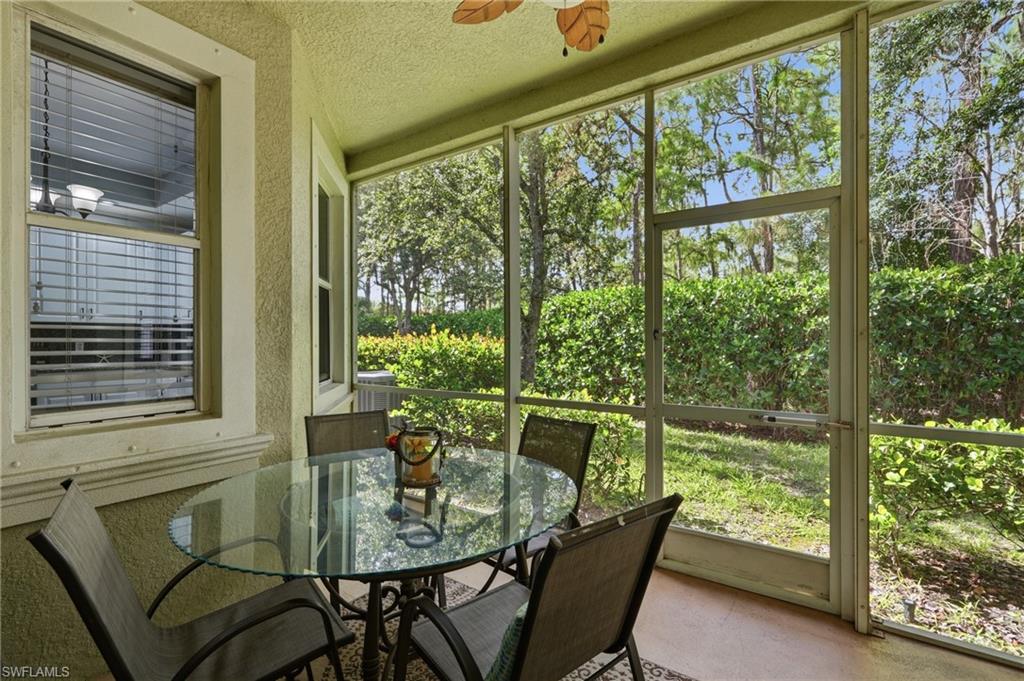 Screened lanai with textured ceiling, outdoor ceiling fan, and direct access to an outdoor area with mature landscaping