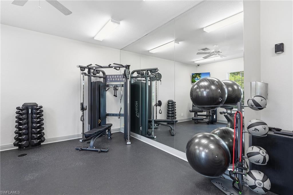 Fitness center with rubber flooring, full-height wall mirrors, and ceiling fan