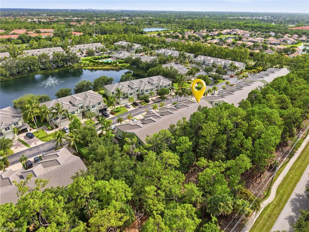 Townhome community with tile roofs, lush green landscaping, and a nearby water feature with a fountain