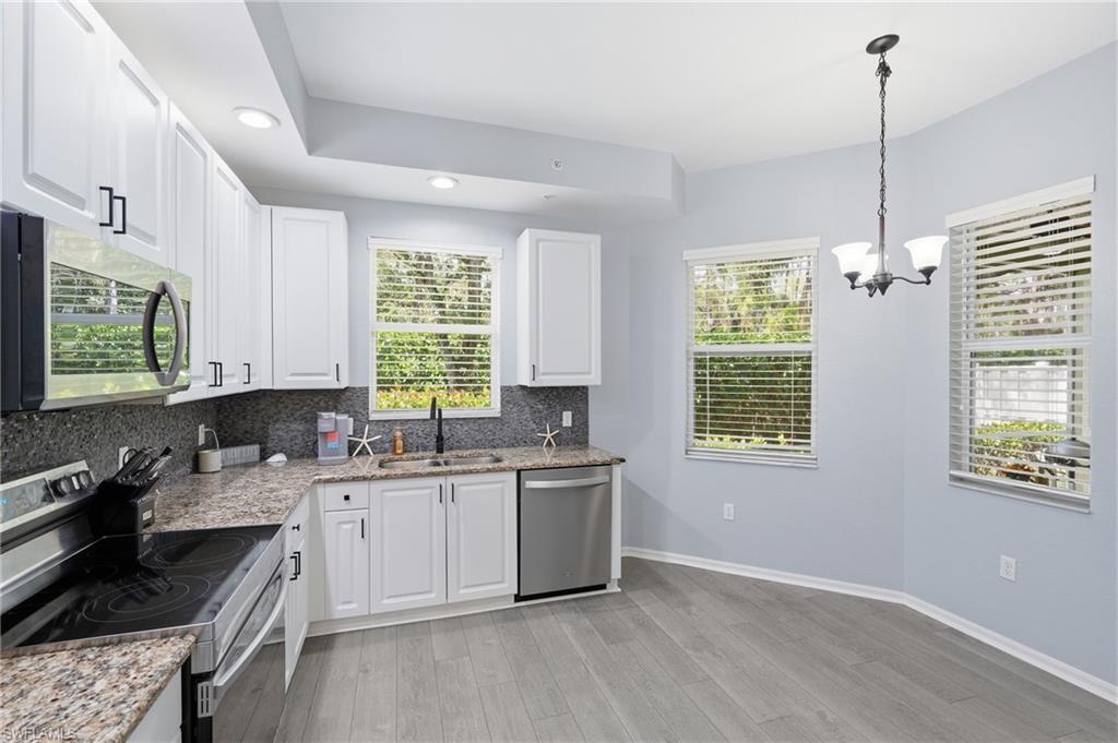 Kitchen featuring white cabinetry, granite countertops, stainless steel appliances, wood-finish flooring, and recessed lighting