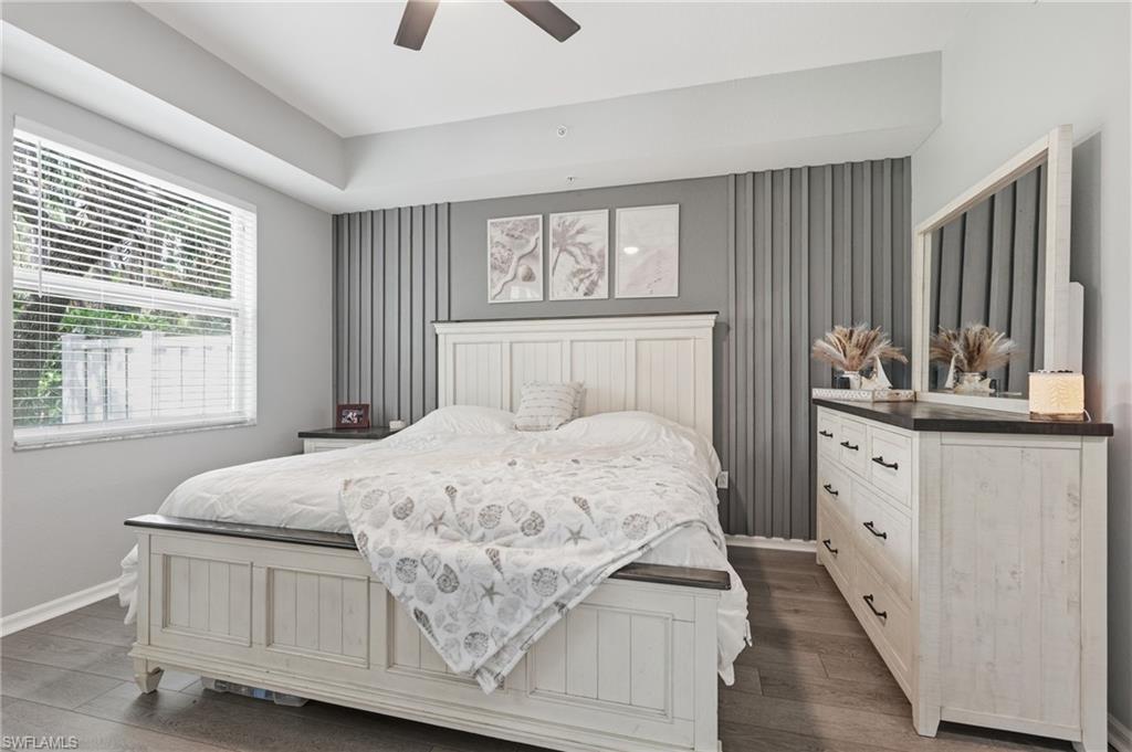 Tray ceiling, wood-finish flooring, ceiling fan, and decorative wall paneling