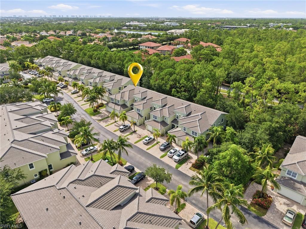 Townhome community featuring tiled roofs, individual driveways, and lush landscaping