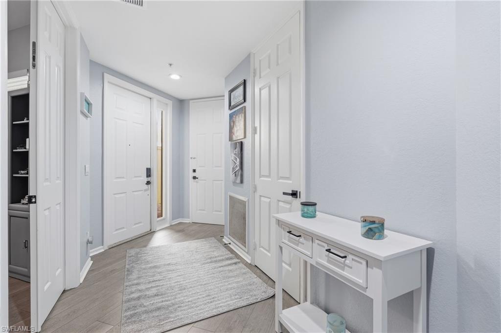 Recessed lighting illuminates the entry, featuring a solid entry door with a sidelight, wood-finish flooring, and crisp white trim