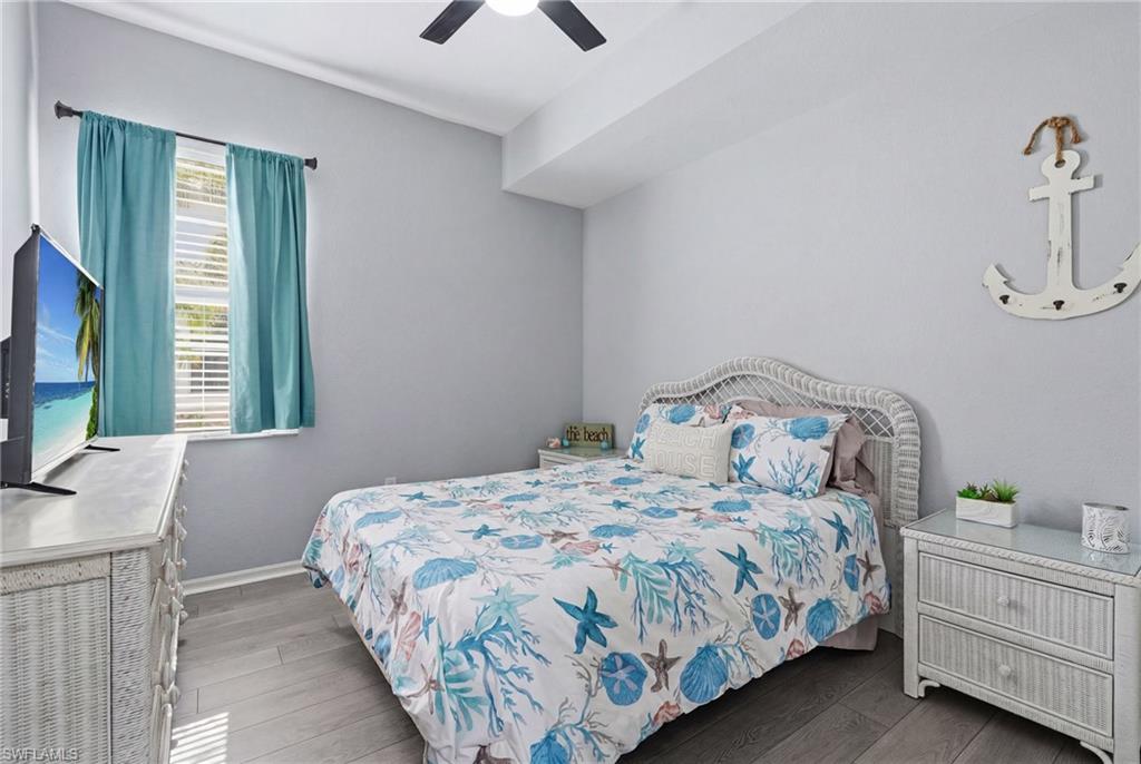 Vaulted ceiling with a ceiling fan, window with horizontal blinds, wood-finish flooring, and light-toned walls