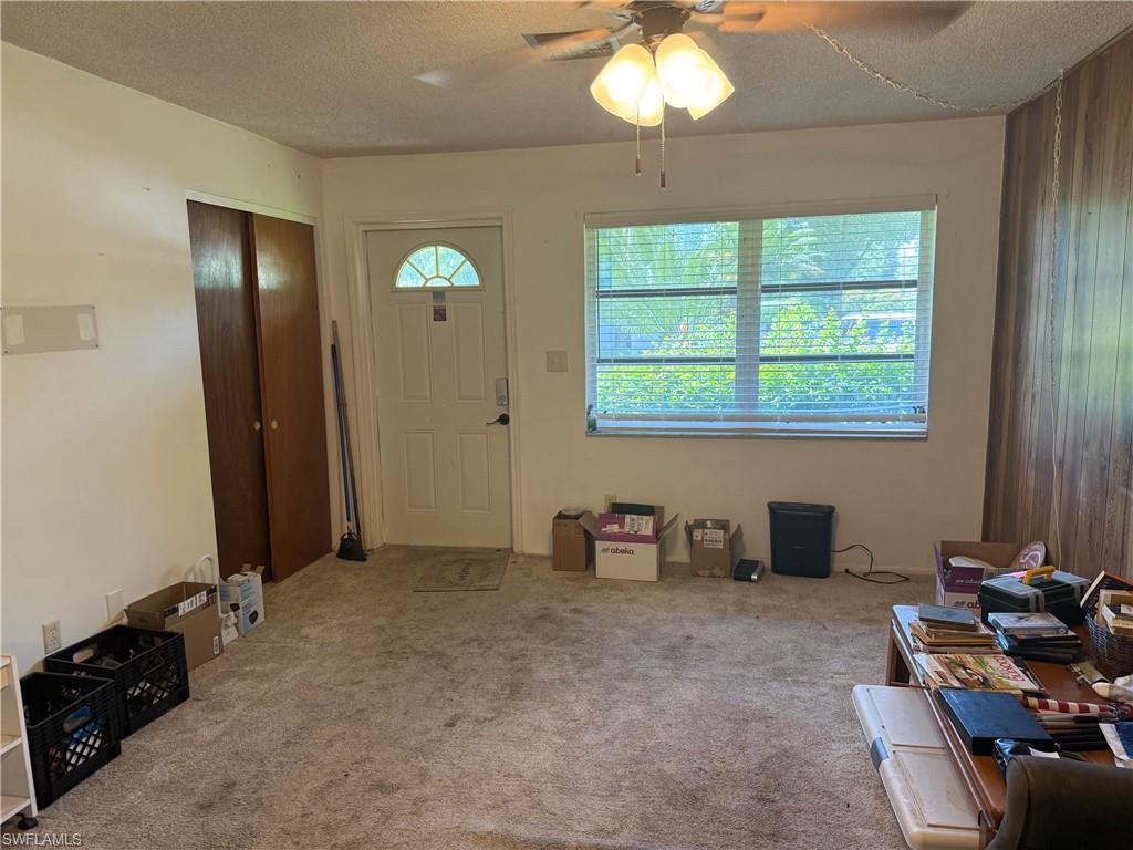 Carpeted interior with a ceiling fan, window with blinds, and a paneled entry door