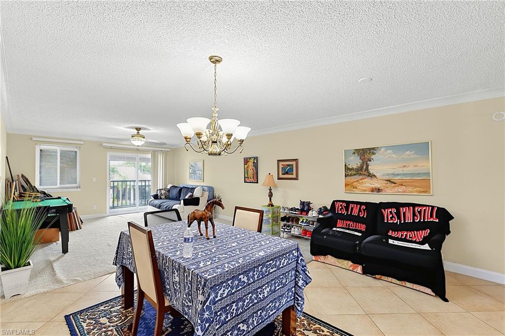 Dining area featuring a brass-finish chandelier, crown molding, and tile flooring