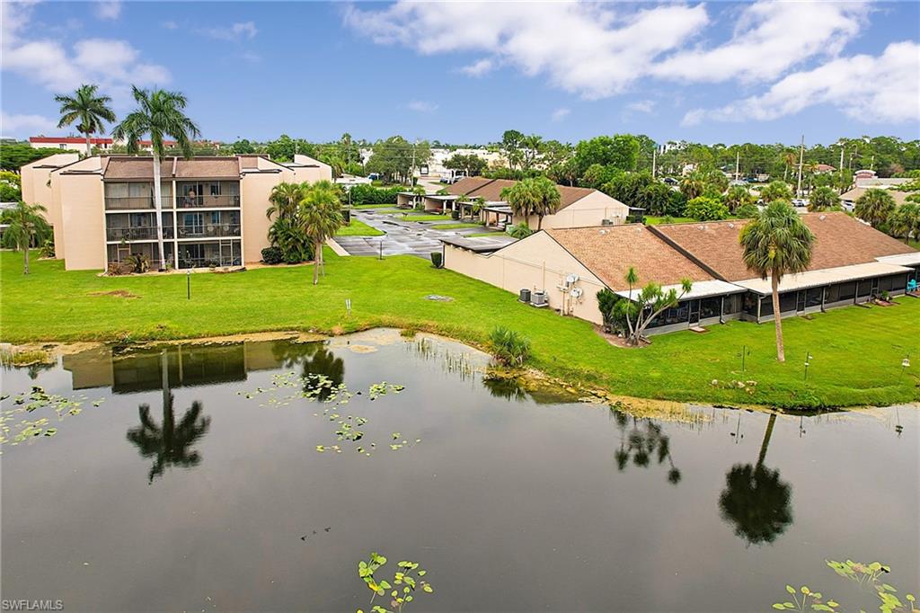 Waterfront property featuring multiple buildings with private screened balconies, mature palm trees, and expansive green spaces