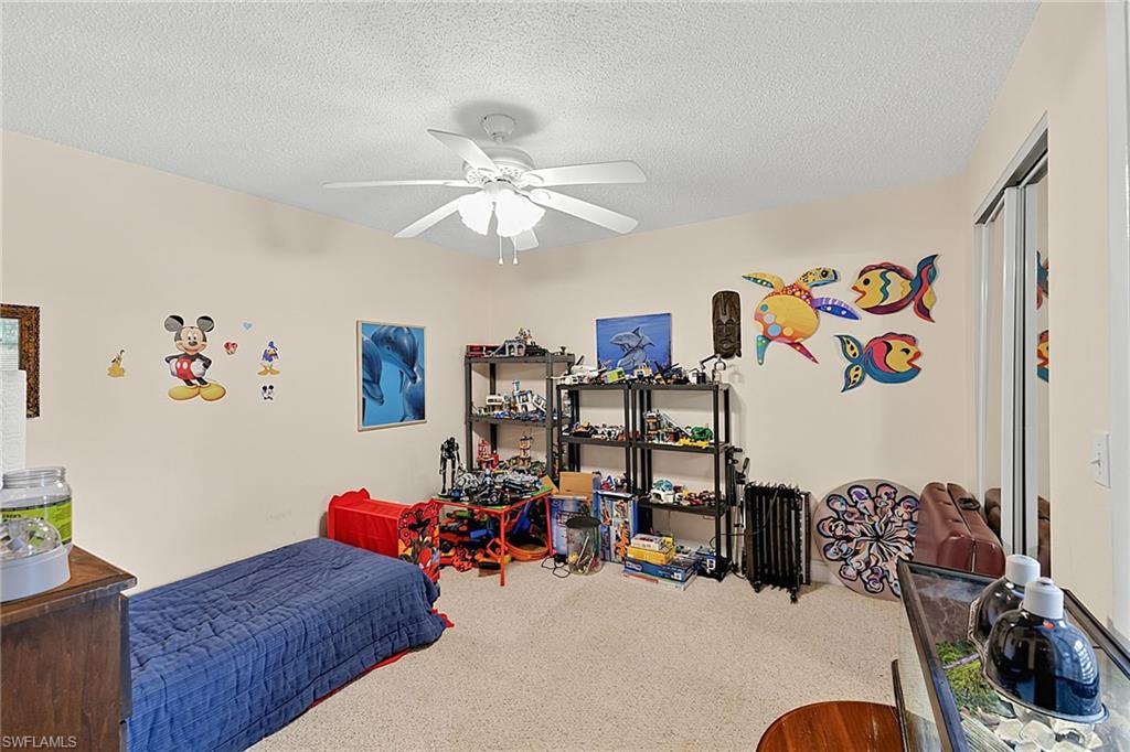 Carpeted room featuring a ceiling fan with light fixture, neutral wall color, and mirrored sliding closet doors