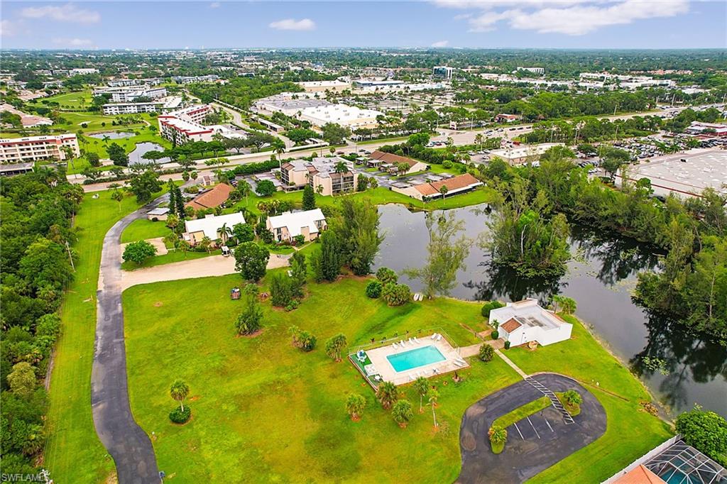 Expansive grounds featuring a swimming pool, a clubhouse with a white stucco exterior, and a paved parking area