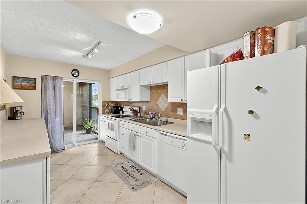 Kitchen featuring white cabinetry, white appliances, neutral countertops, and a tiled backsplash