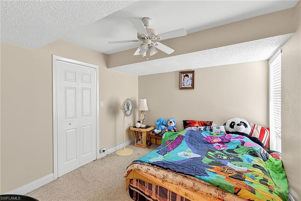 Carpeted room featuring a ceiling fan with light fixture, neutral wall paint, and a white bi-fold closet door