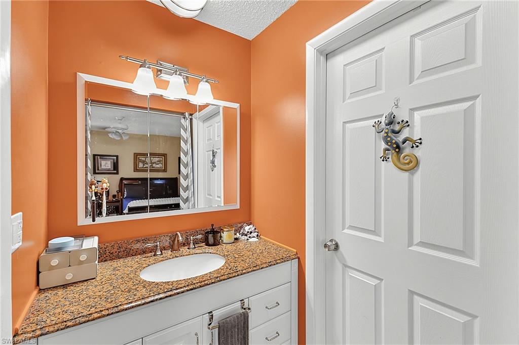 Bathroom vanity featuring a granite countertop, undermount sink, and brushed nickel faucet
