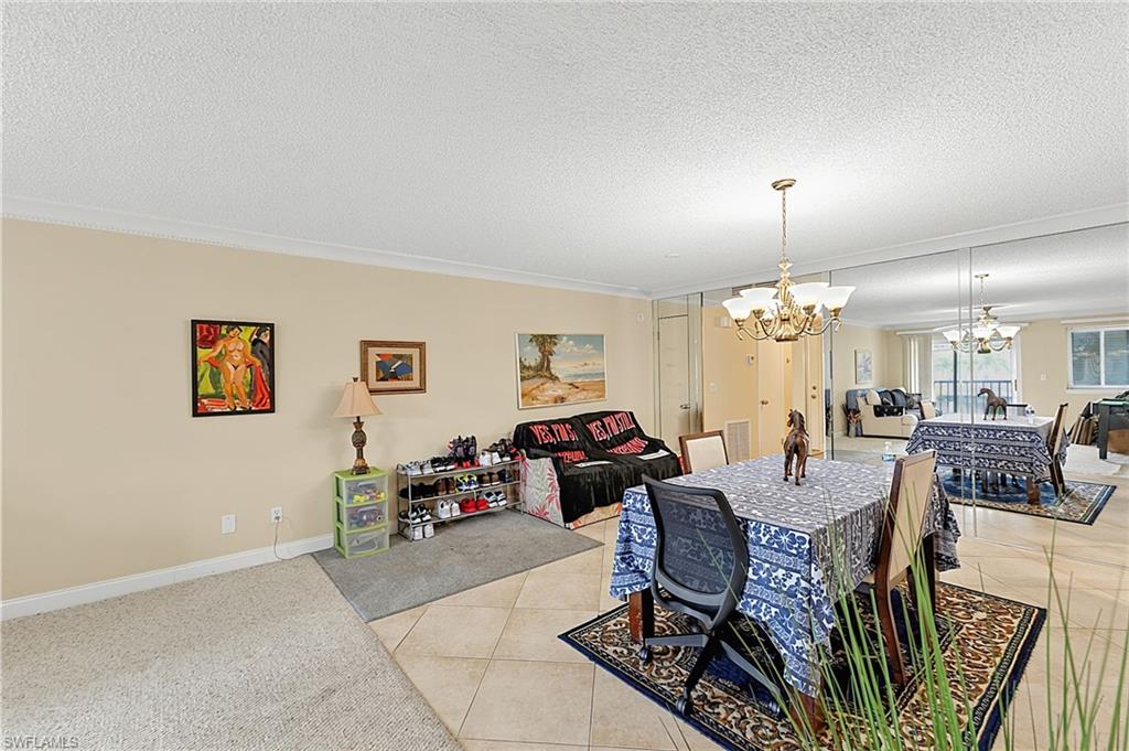 Open concept living and dining area featuring crown molding, neutral wall tones, and varied flooring