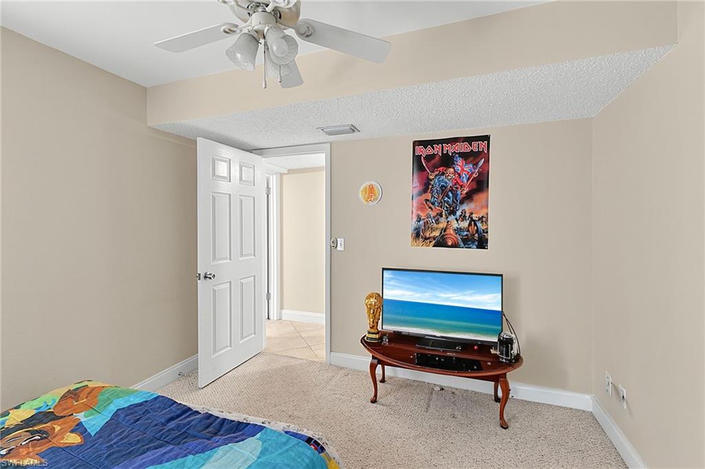 Carpeted room featuring a ceiling fan with integrated lighting, neutral wall tones, and a six-panel interior door