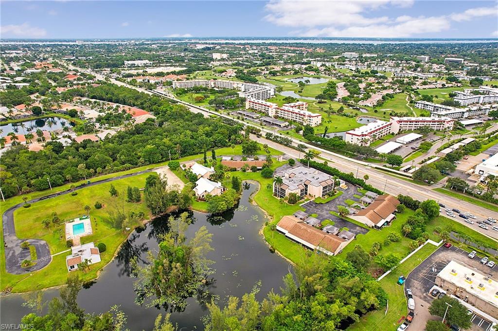 Expansive aerial perspective showcasing a residential community with a large body of water, a private swimming pool, and lush green landscaping