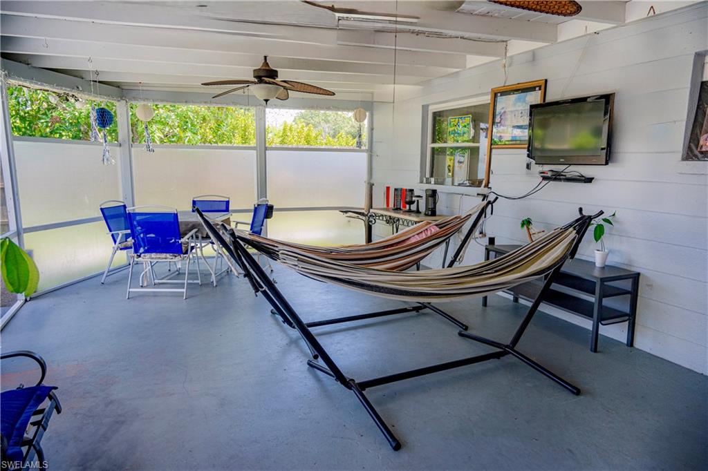 Screened porch featuring exposed beam ceiling, ceiling fan, and painted concrete flooring