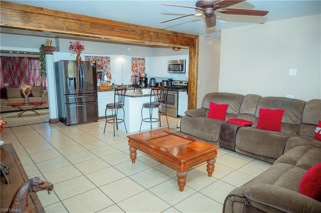 Tile flooring, exposed wood beam, kitchen island, stainless steel refrigerator, stainless steel microwave