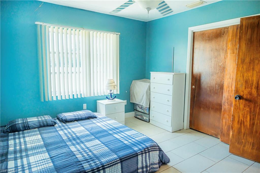 Room with blue walls, tile flooring, a window with vertical blinds, and a ceiling fan