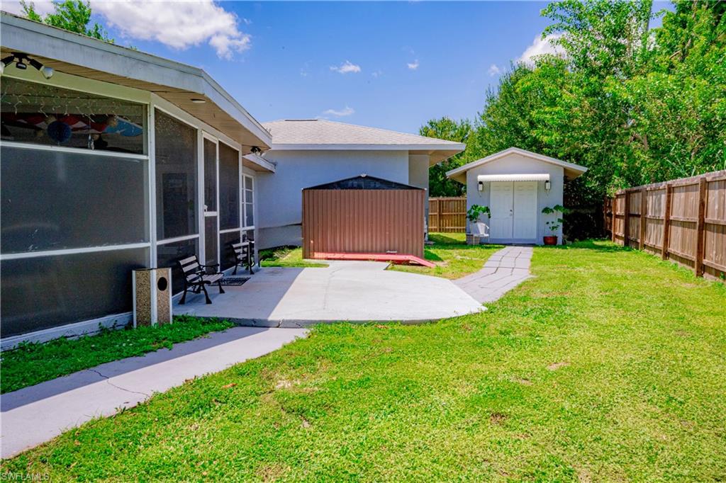 Expansive fenced backyard with a detached shed, screened-in patio, and concrete pathways