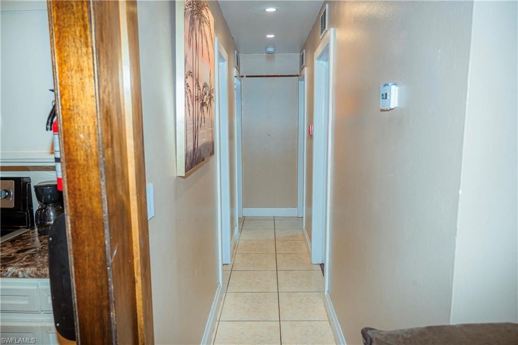 Recessed ceiling lighting, tiled flooring, wood-finish trim, white baseboards, and neutral wall tones