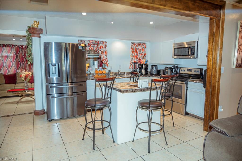 Kitchen featuring stainless steel appliances, recessed lighting, tile flooring, and a breakfast bar with stone-finish countertop